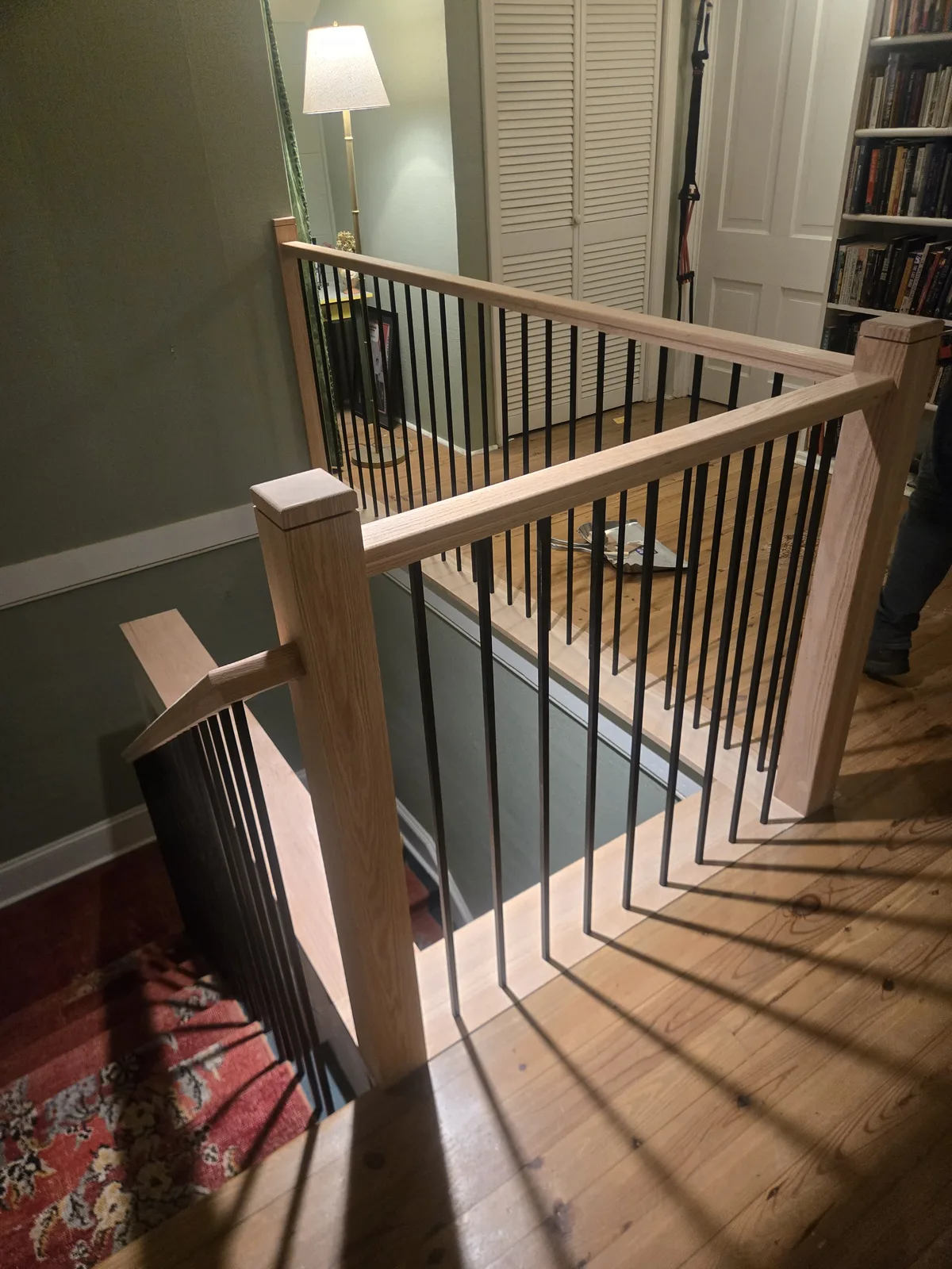 Updated stair landing railing with wood rails and iron balusters