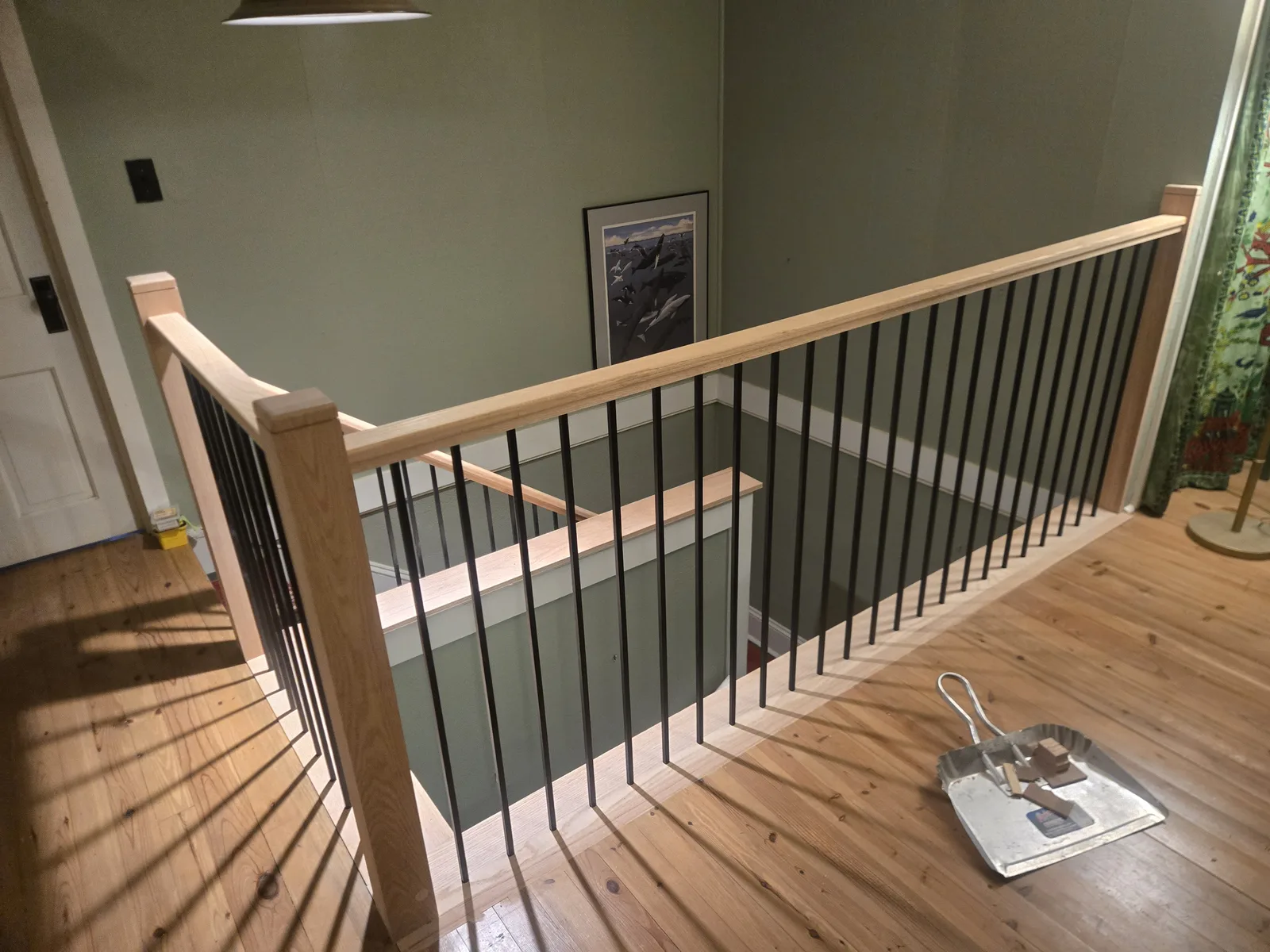 Repaired stairwell railing with iron balusters and wood handrail
