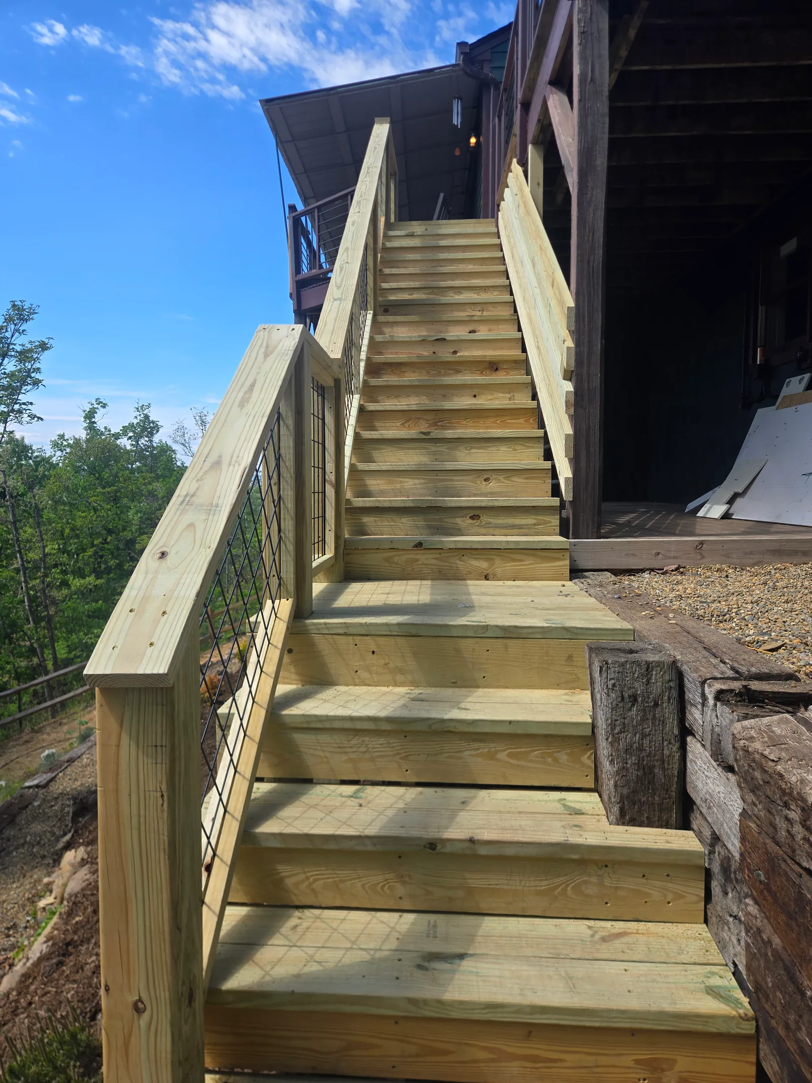 Top landing of a new outdoor staircase with wood guardrails